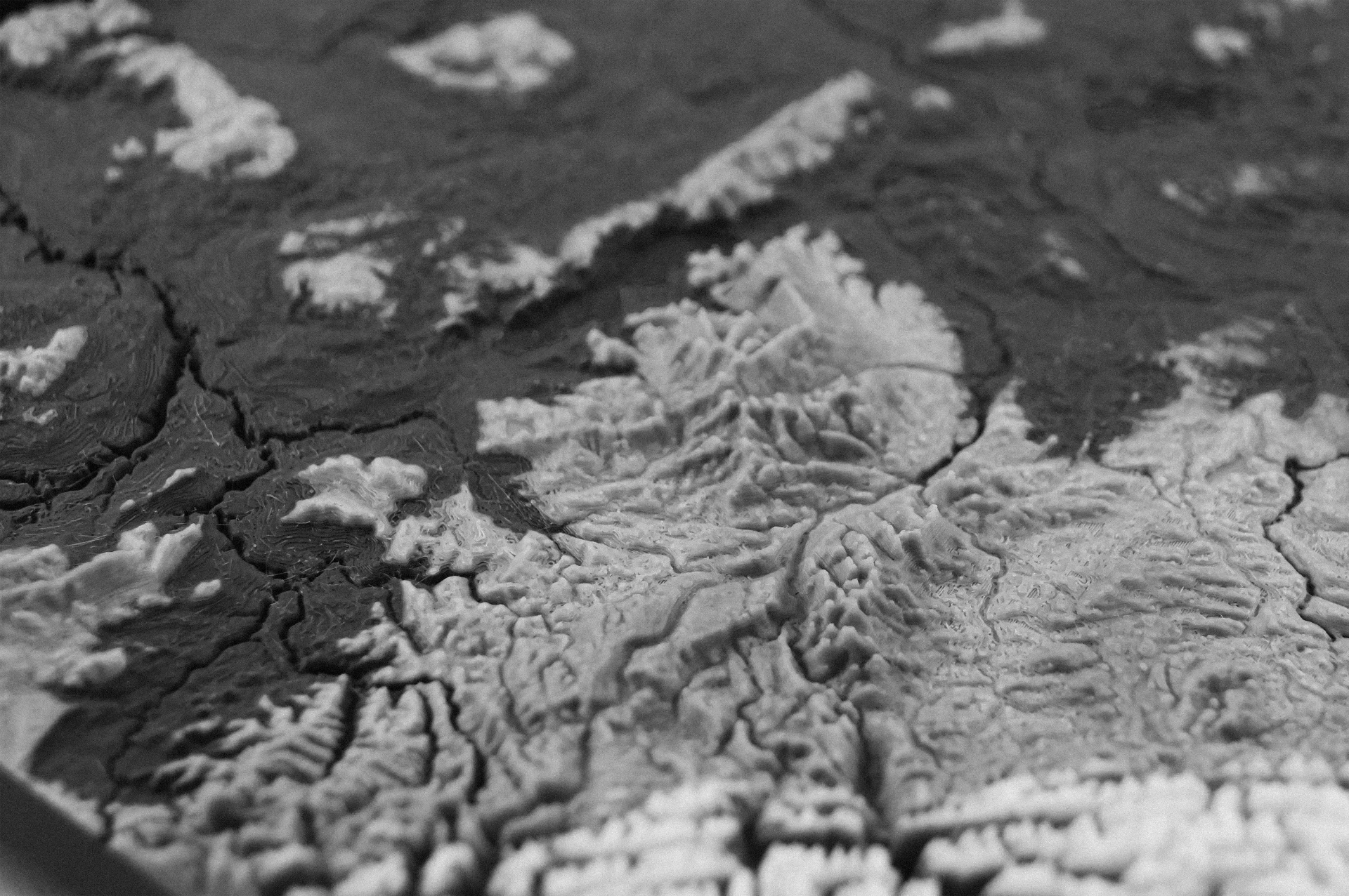 A 3D printed topographic relief model of a mountain landscape, cast in dark concrete